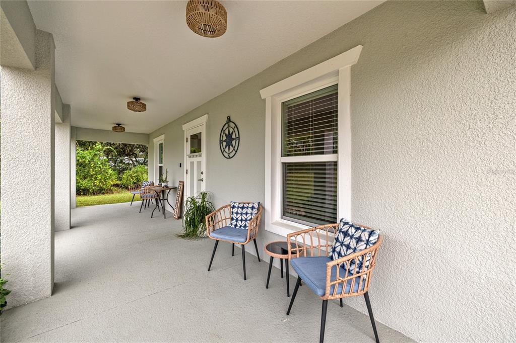 A covered porch features light gray flooring, two wicker chairs with blue pillows, and a window — 53 OLIVE ROAD, OCALA, FL