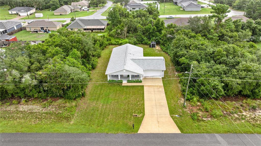 An aerial view shows a single-story house with a concrete driveway surrounded by dense trees — 53 OLIVE ROAD, OCALA, FL