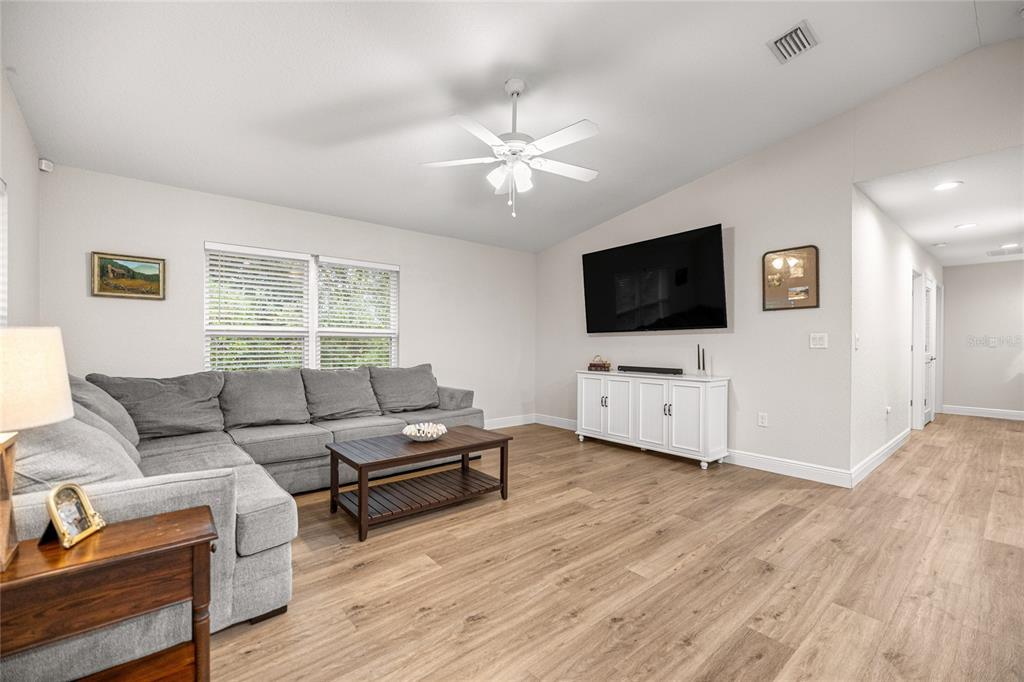 A living room features a gray sectional sofa, a wooden coffee table, and a wall-mounted television — 53 OLIVE ROAD, OCALA, FL