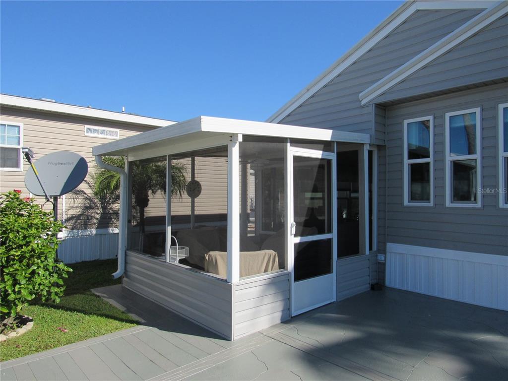 A screened-in porch with white framing is attached to the side of a gray house — 9000 US HWY 192 UNIT 600, CLERMONT, FL