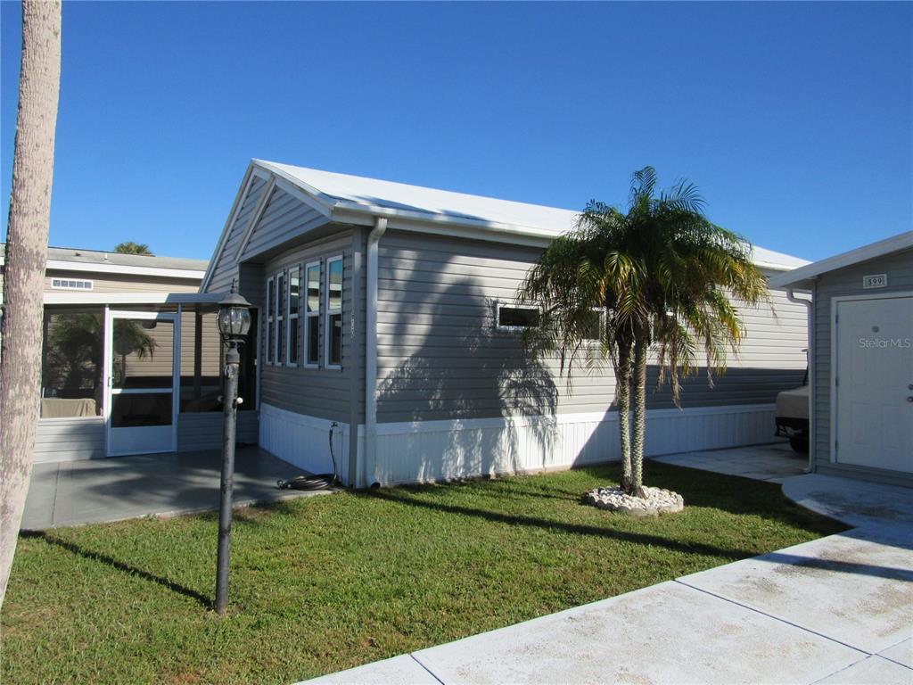 A gray manufactured home with a white roof, a small palm tree, and a patio — 9000 US HWY 192 UNIT 600, CLERMONT, FL