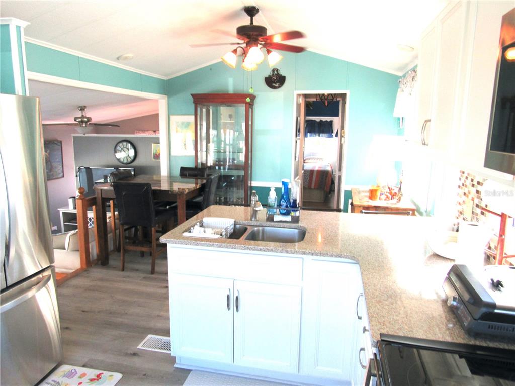 A kitchen with white cabinets, granite countertops, and a view into the dining area — 9000 US HWY 192 UNIT 600, CLERMONT, FL