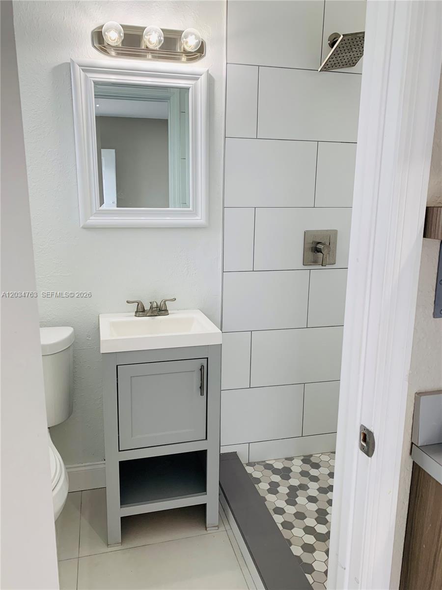A small bathroom features a gray vanity, a white toilet, and a tiled walk-in shower — 1265 SW 6th St # 13, Miami FL 33135, MIAMI, FL