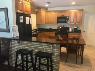 A kitchen features light wood cabinets, black countertops, a brick-faced breakfast bar, and stools — 817 S B Street, FL 33460, FL