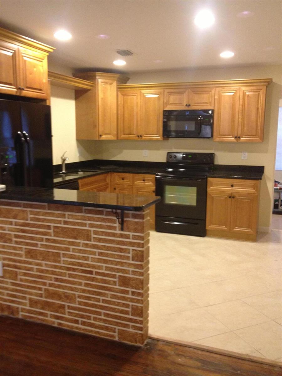 A kitchen features light wood cabinets, black appliances, dark countertops, and a brick-faced breakfast bar — 817 S B Street, FL 33460, FL
