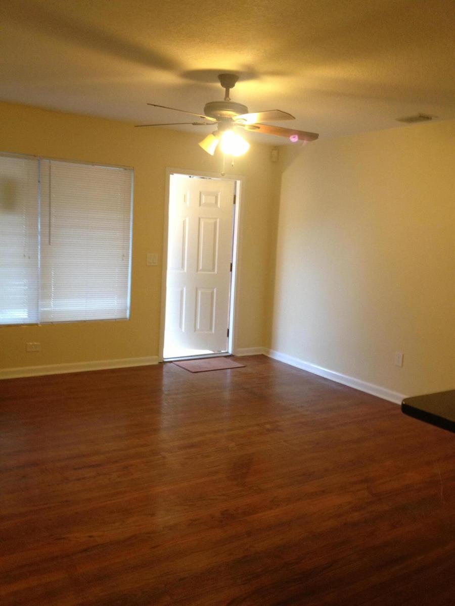 An empty room with wood-look flooring, a ceiling fan, and an open exterior door — 817 S B Street, FL 33460, FL