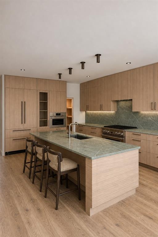 A modern kitchen features light wood cabinetry, a green stone island, and stainless steel appliances — 1680 CHERRY LANE, SARASOTA, FL