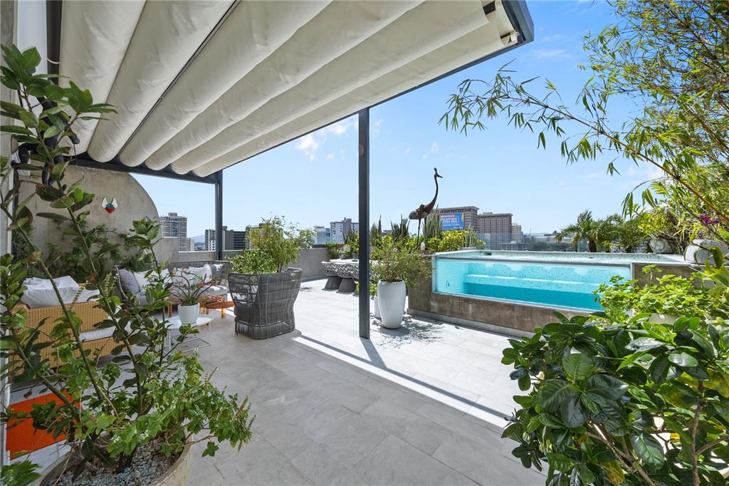 A rooftop terrace features a glass-walled pool, outdoor seating, and a retractable fabric canopy — 1360 LUCHETTI STREET, CROWNE PLAZA UNIT PH, SAN JUAN, PR