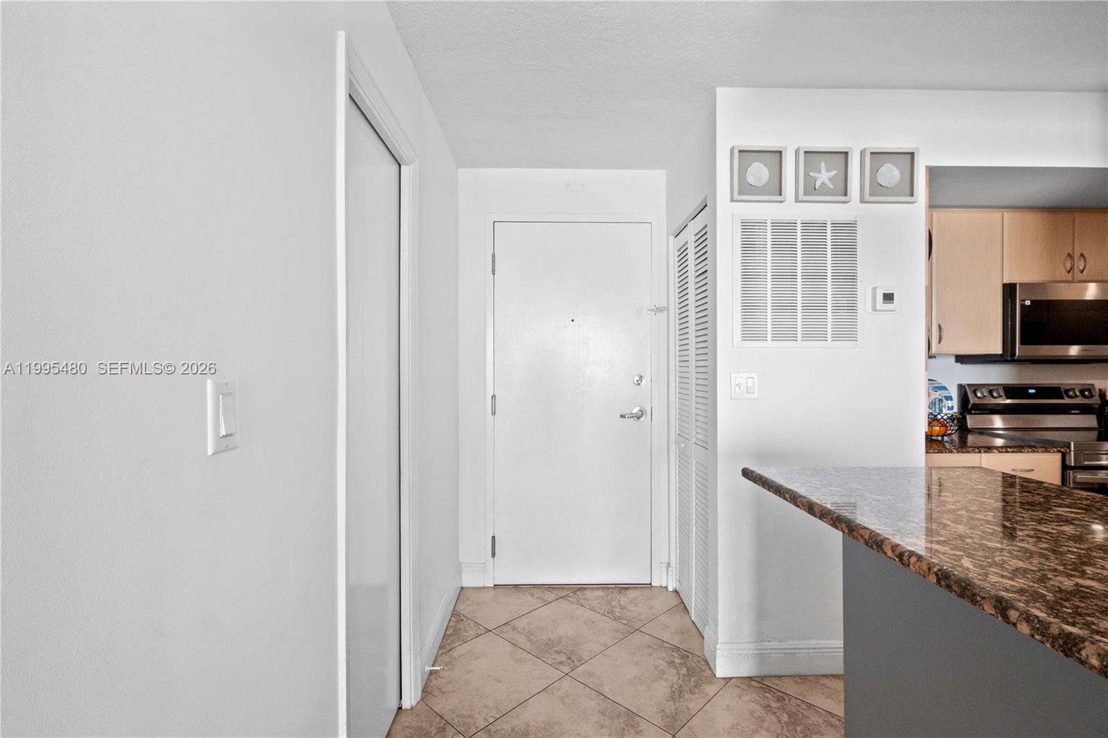 The image shows an entryway with tile flooring, a white door, and a kitchen counter — 6917 Collins Ave # 1609, Miami Beach FL 33141, MIAMI BEACH, FL