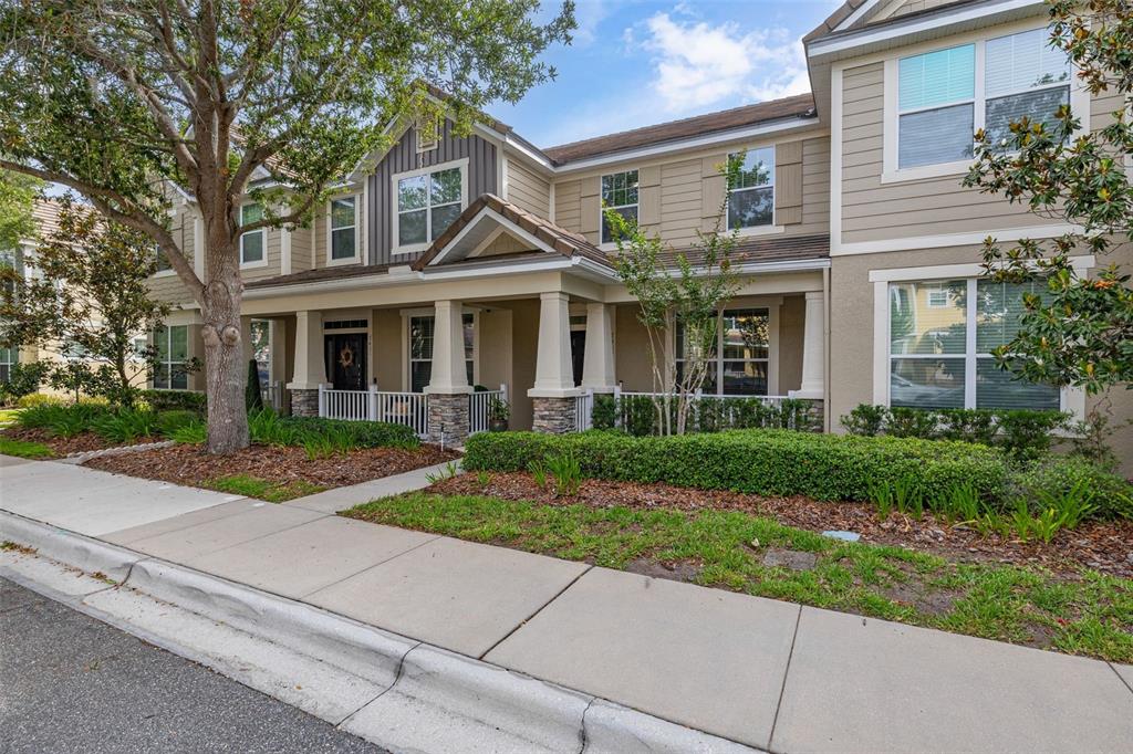 A two-story townhouse exterior features tan siding, stone accents, and a covered front porch — 7435 RIPPLEPOINTE WAY, WINDERMERE, FL