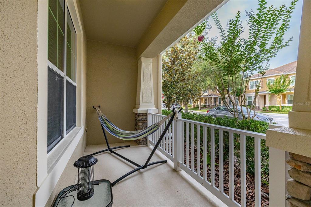 A covered porch features a hammock, a small table with a lamp, and white railings — 7435 RIPPLEPOINTE WAY, WINDERMERE, FL