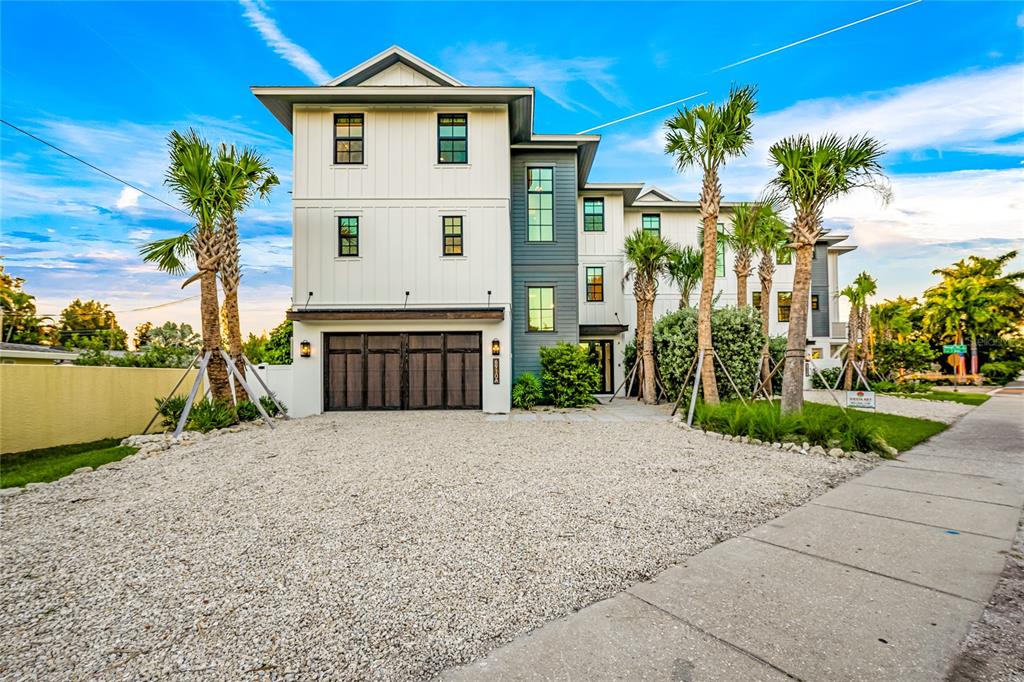 A three-story modern house with white vertical siding, gray accents, and a gravel driveway — 6910 MIDNIGHT PASS ROAD UNIT B, SARASOTA, FL