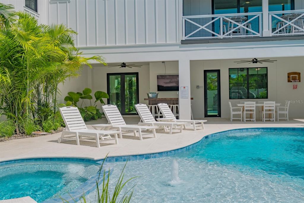 A swimming pool and spa sit in front of a covered patio with lounge chairs — 6910 MIDNIGHT PASS ROAD UNIT B, SARASOTA, FL