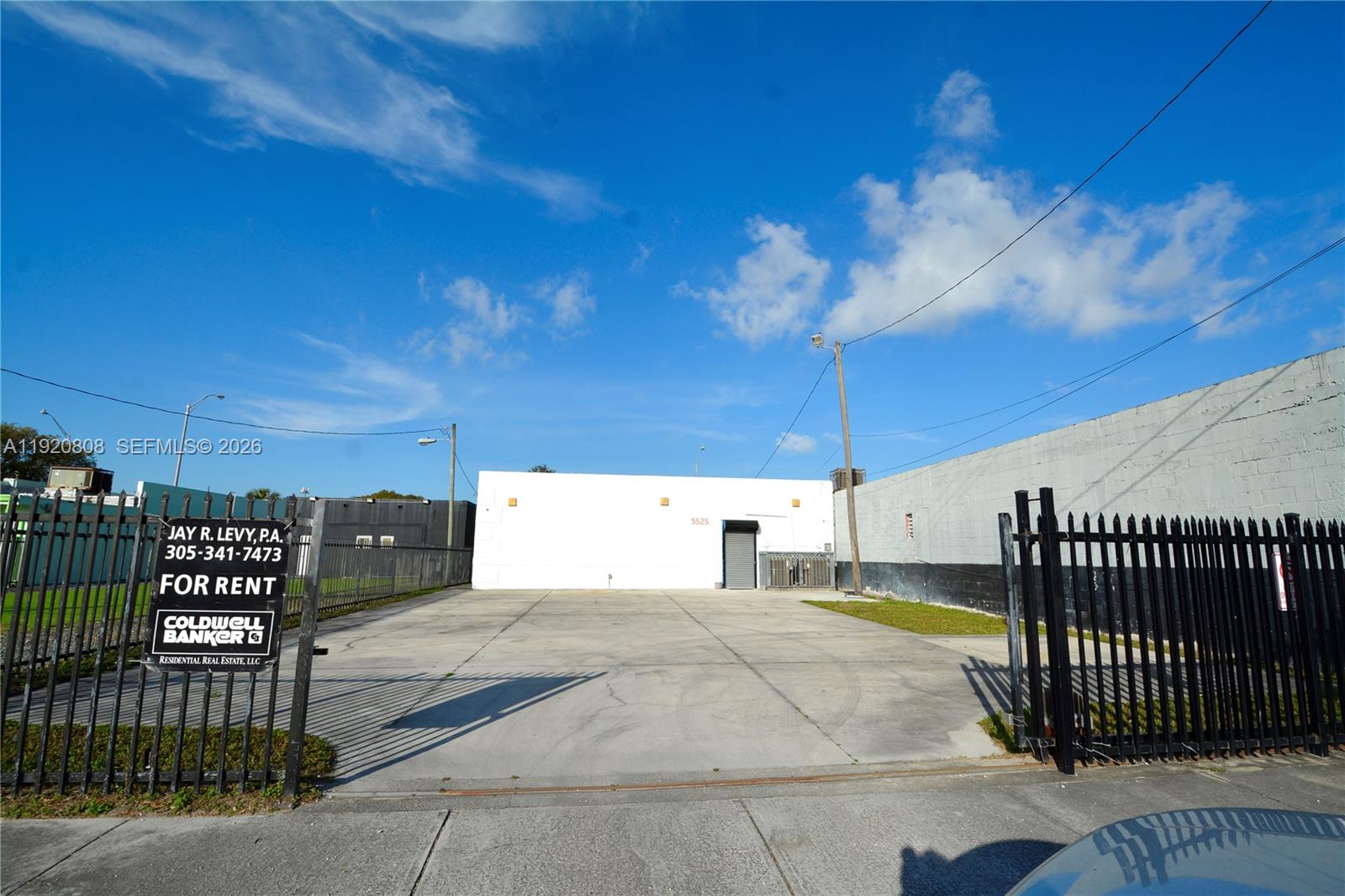 A paved lot leads to a white industrial building behind a black metal fence — 5525 NW 7th Ave, Miami FL 33127, MIAMI, FL