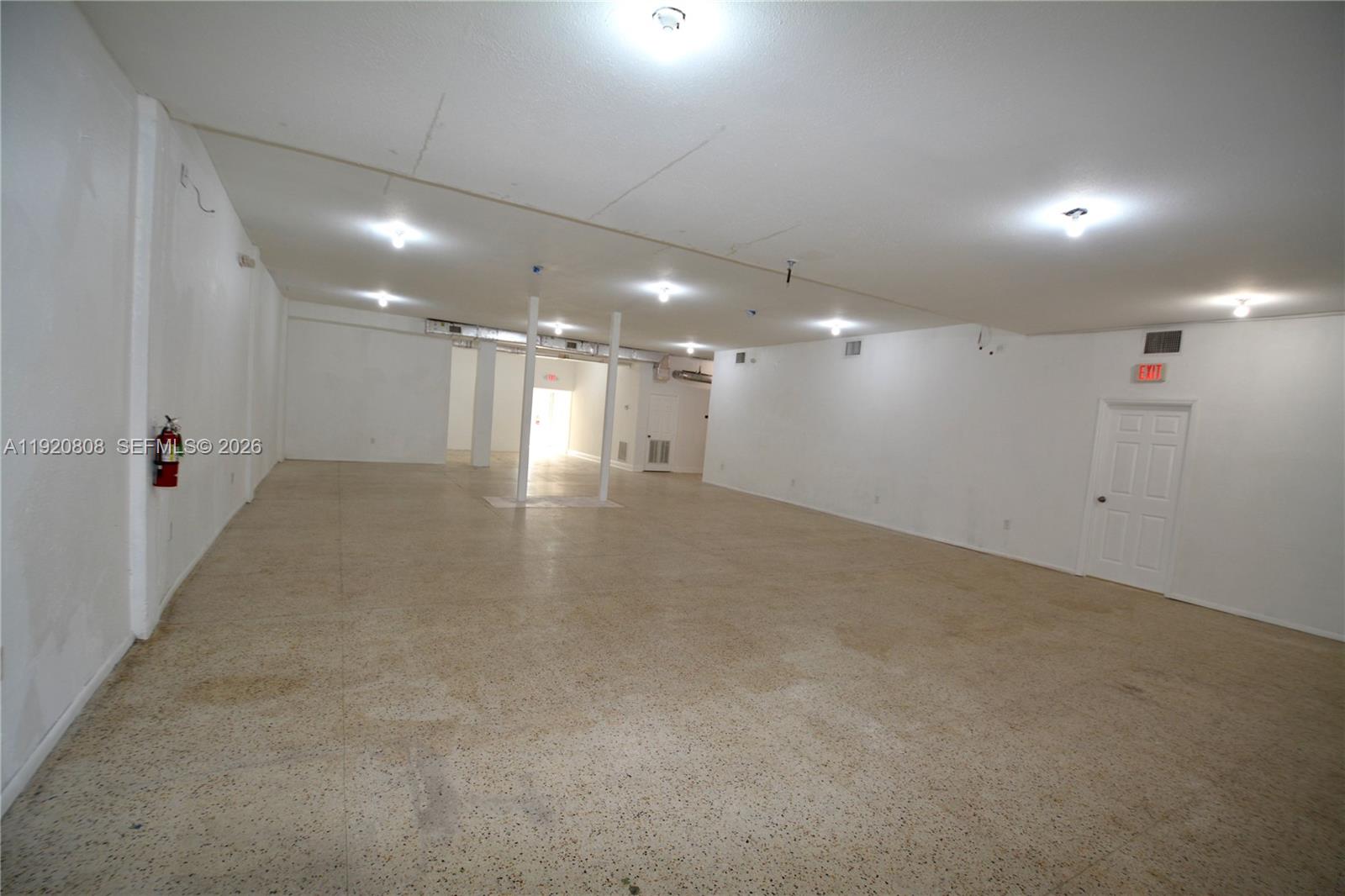 A large, empty commercial space features white walls, a speckled floor, and overhead lighting — 5525 NW 7th Ave, Miami FL 33127, MIAMI, FL