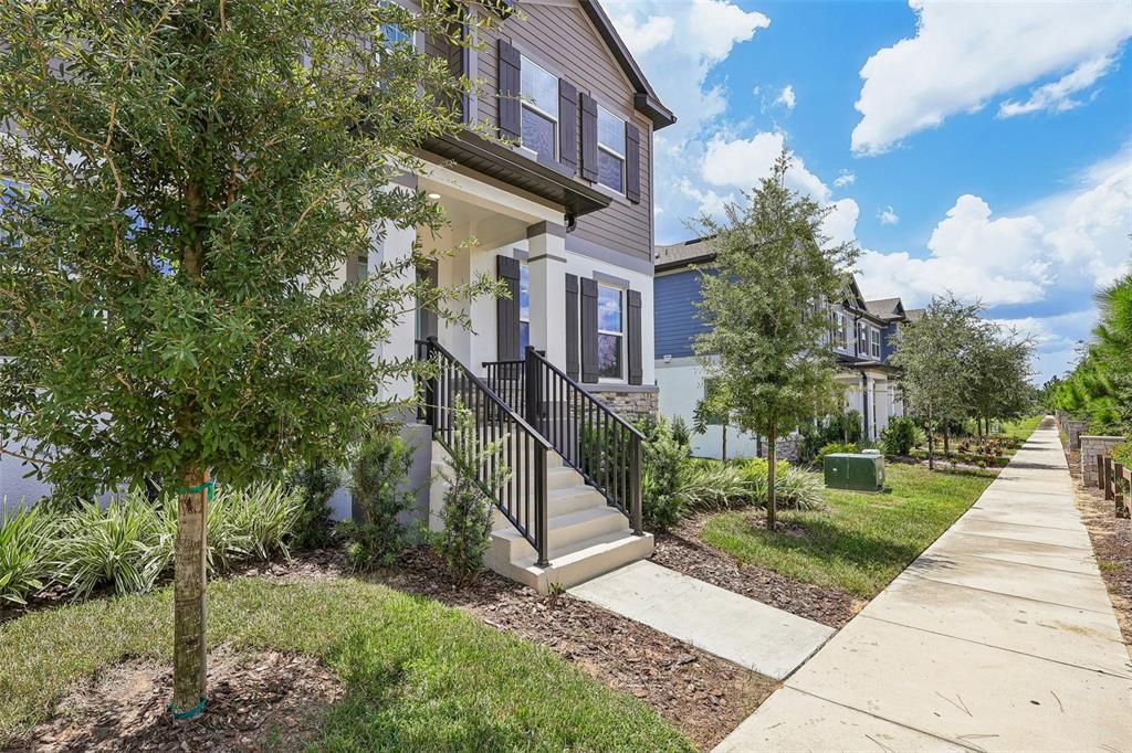 A multi-story house with a front porch, stairs, and a sidewalk along the side — 15877 TOLLINGTON ALLEY, WINTER GARDEN, FL