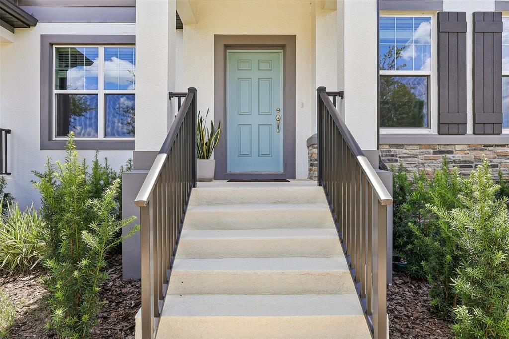 A light blue front door is centered at the top of concrete steps with railings — 15877 TOLLINGTON ALLEY, WINTER GARDEN, FL