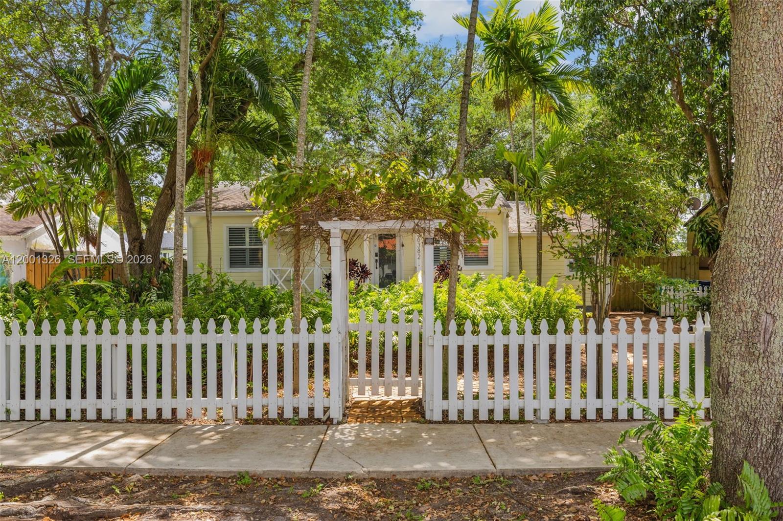 A white picket fence surrounds the front yard of a yellow cottage-style house — 6382 SW 38th St, Miami FL 33155, MIAMI, FL