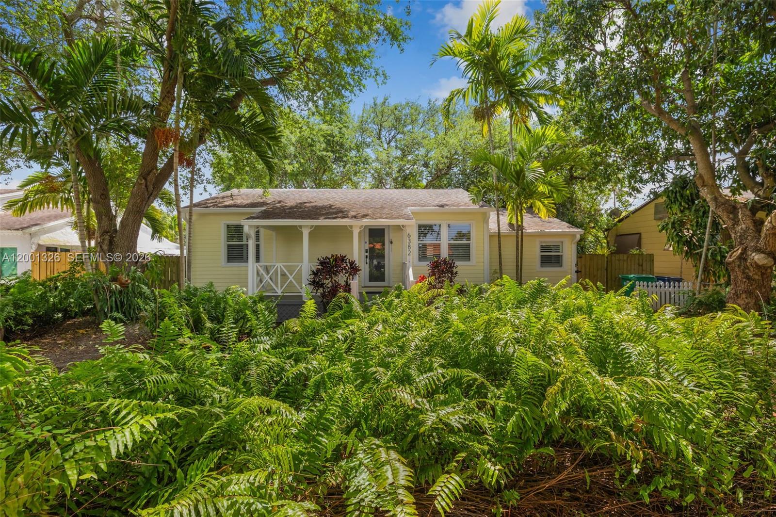 A yellow single-story house with a front porch is surrounded by lush tropical landscaping — 6382 SW 38th St, Miami FL 33155, MIAMI, FL