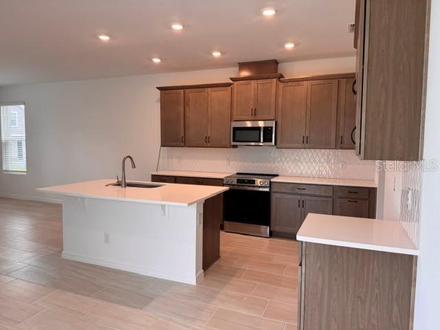 A kitchen features light wood cabinets, a white island with a sink, and tile flooring — 392 OAK FLAT ALLEY, GROVELAND, FL