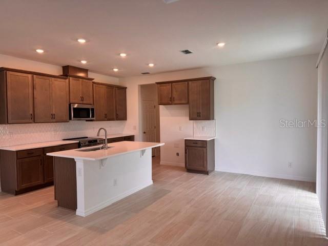 A kitchen features brown wooden cabinets, a white island with a sink, and light-colored flooring — 392 OAK FLAT ALLEY, GROVELAND, FL
