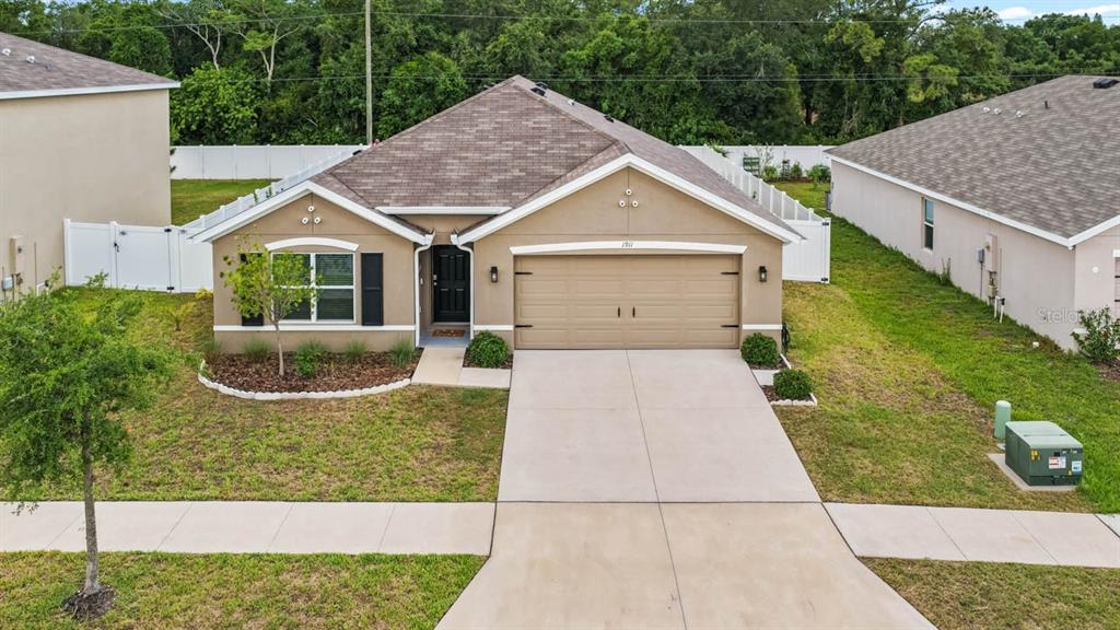 An aerial view of a single-story suburban house with a tan stucco exterior and garage — 1911 BLUE STREAM STREET, RUSKIN, FL