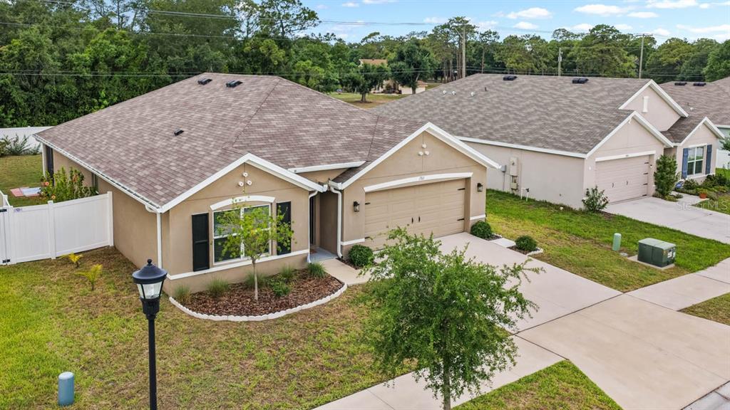 An aerial view shows a tan, single-story suburban house with a brown shingled roof — 1911 BLUE STREAM STREET, RUSKIN, FL