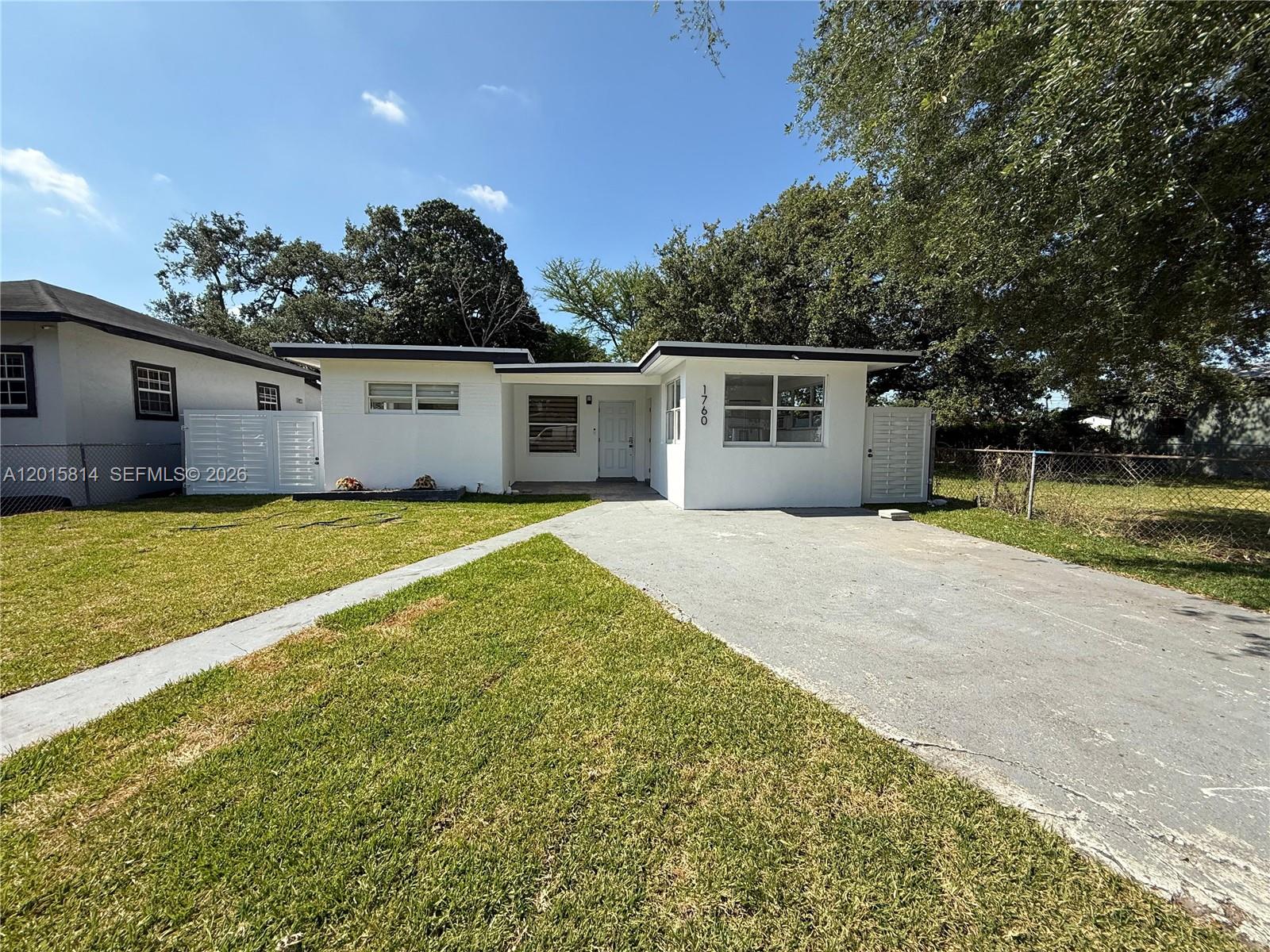 A white, single-story house features a flat roof, a concrete driveway, and a front lawn — 1760 NW 84th St, Miami FL 33147, MIAMI, FL