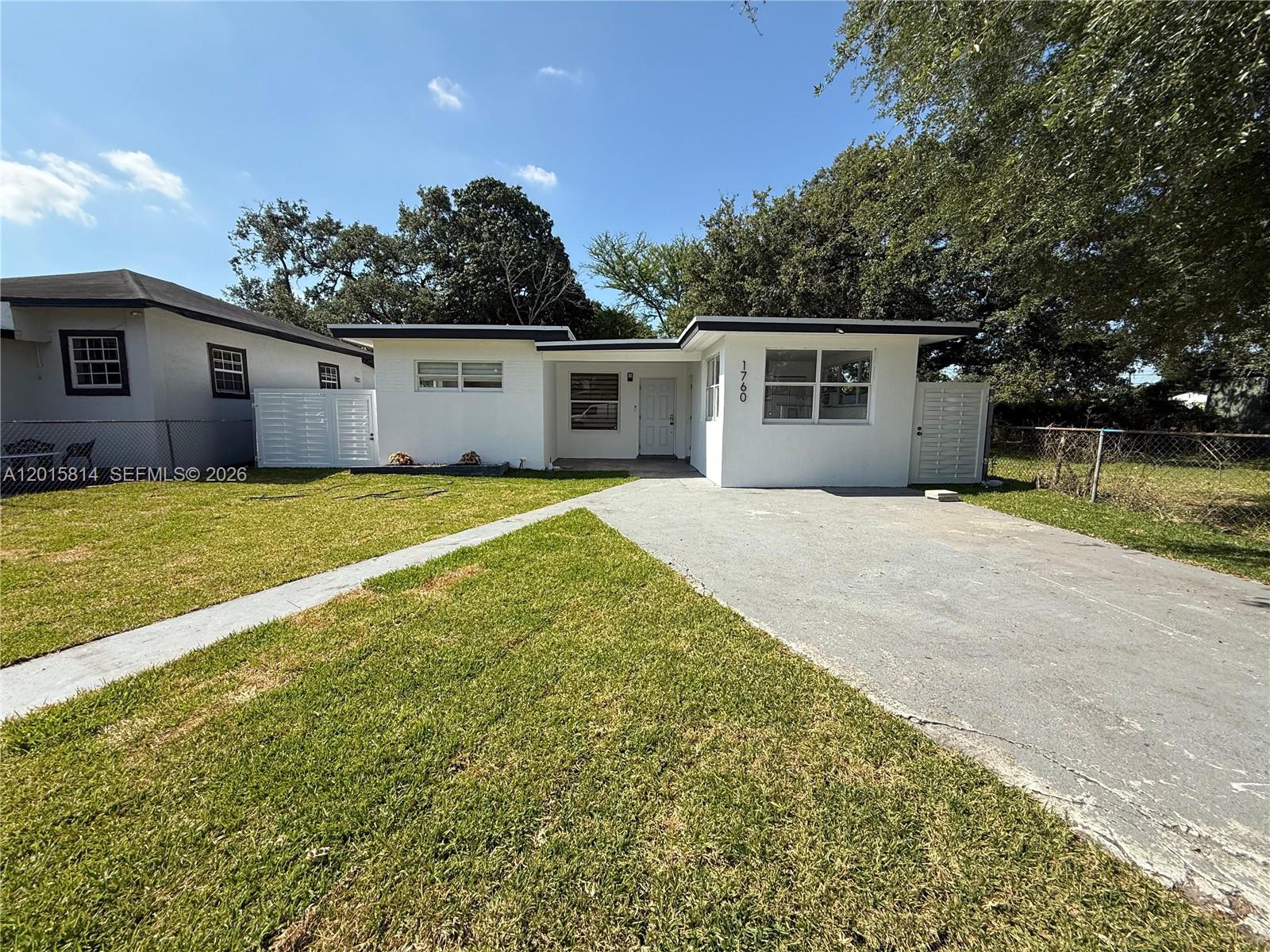 A white single-story house with a flat roof and a concrete driveway sits on grass — 1760 NW 84th St, Miami FL 33147, MIAMI, FL