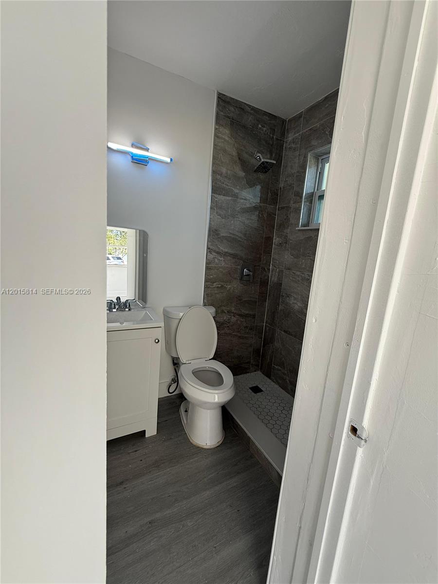 A small bathroom features a pedestal sink, a toilet, and a tiled walk-in shower — 1760 NW 84th St, Miami FL 33147, MIAMI, FL