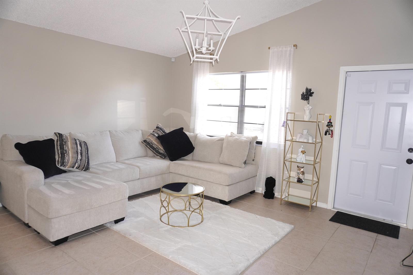 A living room features a beige sectional sofa, a gold coffee table, and a gold shelf — 8731 Uranus Terrace, West Palm Beach FL 33403, WEST PALM BEACH, FL