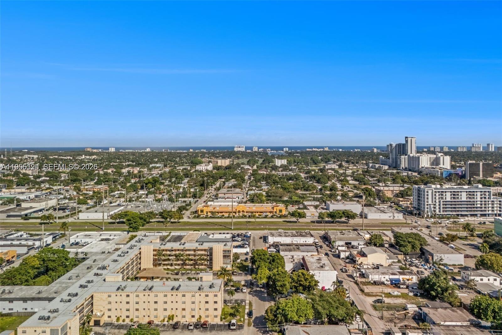 An aerial view shows a suburban landscape with buildings, trees, and a distant coastline — 2145 Pierce St # 326, Hollywood FL 33020, HOLLYWOOD, FL