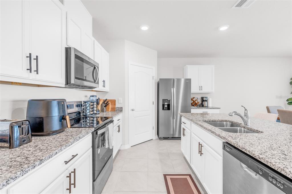 A modern kitchen features white cabinets, granite countertops, stainless steel appliances, and a central island — 1022 TUPELO TRAIL, HAINES CITY, FL