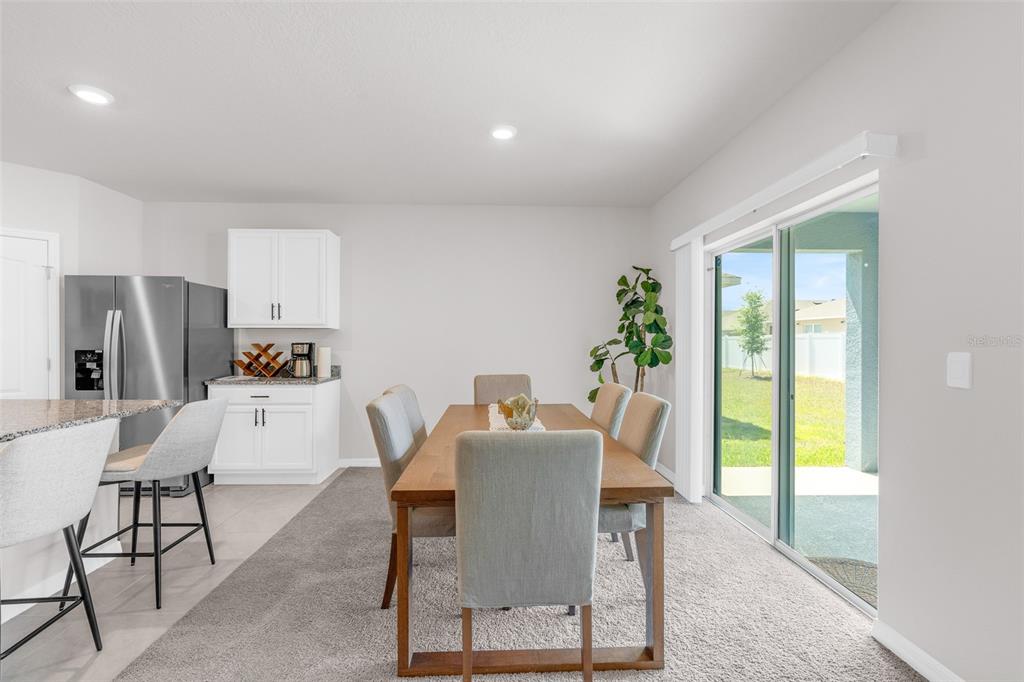 A dining area features a wooden table, six upholstered chairs, and a sliding glass door — 1022 TUPELO TRAIL, HAINES CITY, FL