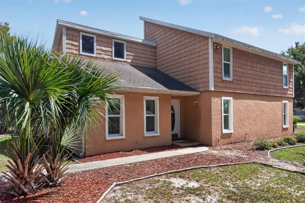 A two-story house with tan stucco, brown shingle siding, and a palm tree in front — 1720 SUNSET VIEW CIRCLE, APOPKA, FL