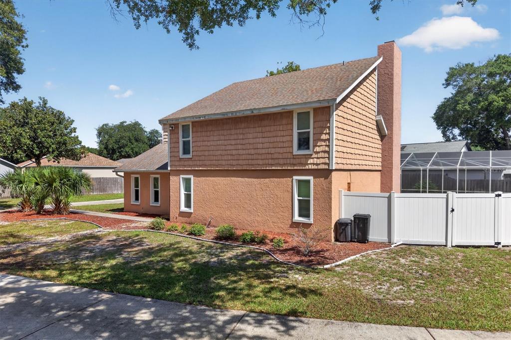 The exterior of a two-story house with tan stucco and shingle siding and a chimney — 1720 SUNSET VIEW CIRCLE, APOPKA, FL