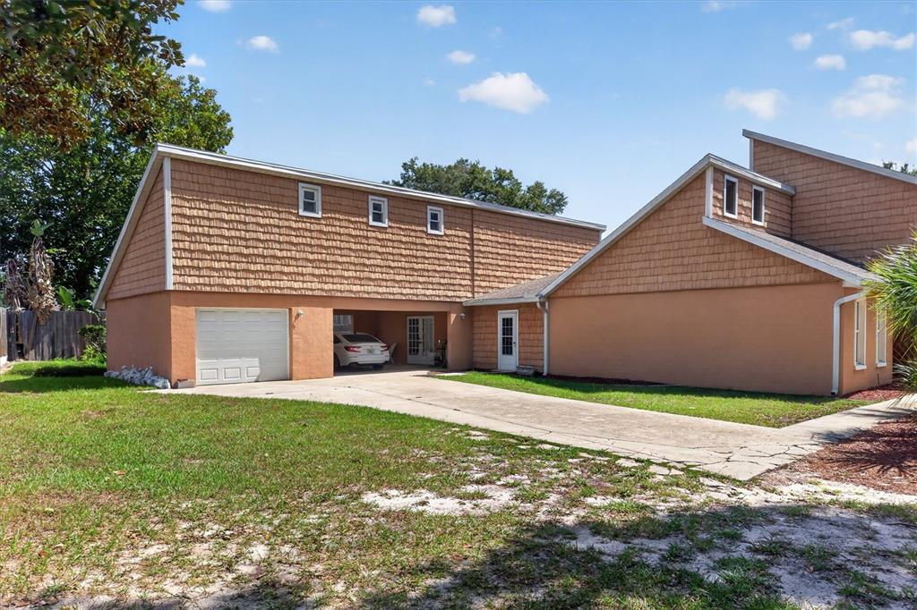 A two-story house with a tan stucco and shingle exterior, a garage, and a carport — 1720 SUNSET VIEW CIRCLE, APOPKA, FL