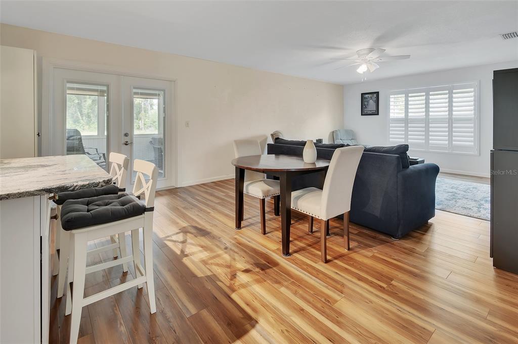 An open-concept living and dining area features wood-look flooring, a kitchen island, and patio doors — 720 S HILL AVENUE UNIT 8B, DELAND, FL