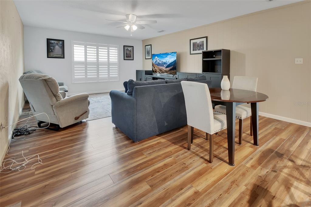 A living and dining area features wood-look flooring, a blue sofa, and a dining set — 720 S HILL AVENUE UNIT 8B, DELAND, FL