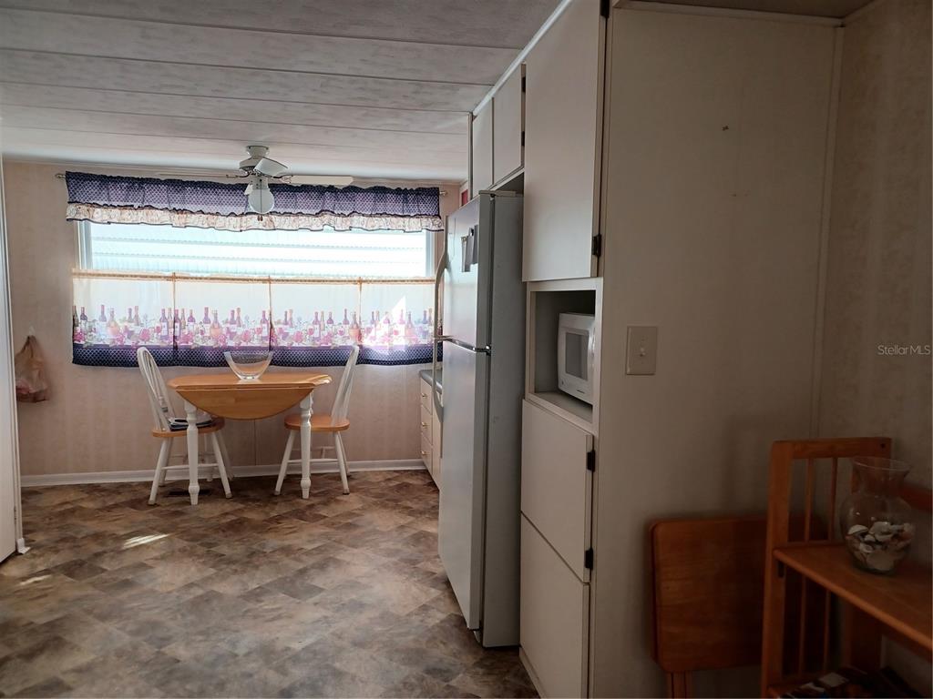A kitchen features a small dining table, a refrigerator, and a built-in microwave — 34701 ROSEBUD ROW, ZEPHYRHILLS, FL