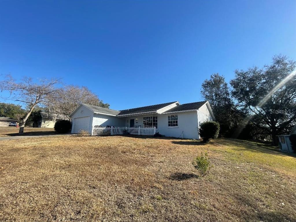 A single-story house with a white exterior, a white picket fence, and a two-car garage — 36422 BIRDIE COURT, GRAND ISLAND, FL