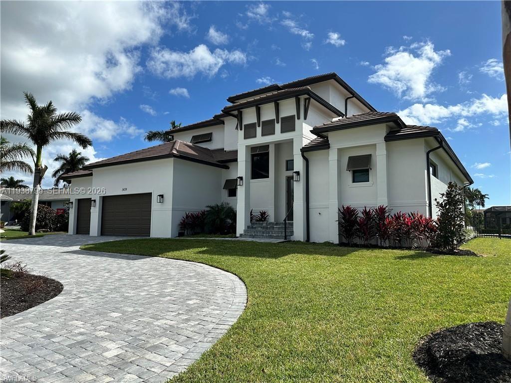 A two-story white house with a brown garage and a paved driveway under a sky — 654 Bamboo Ct, Marco Island FL 34145, MARCO ISLAND, FL