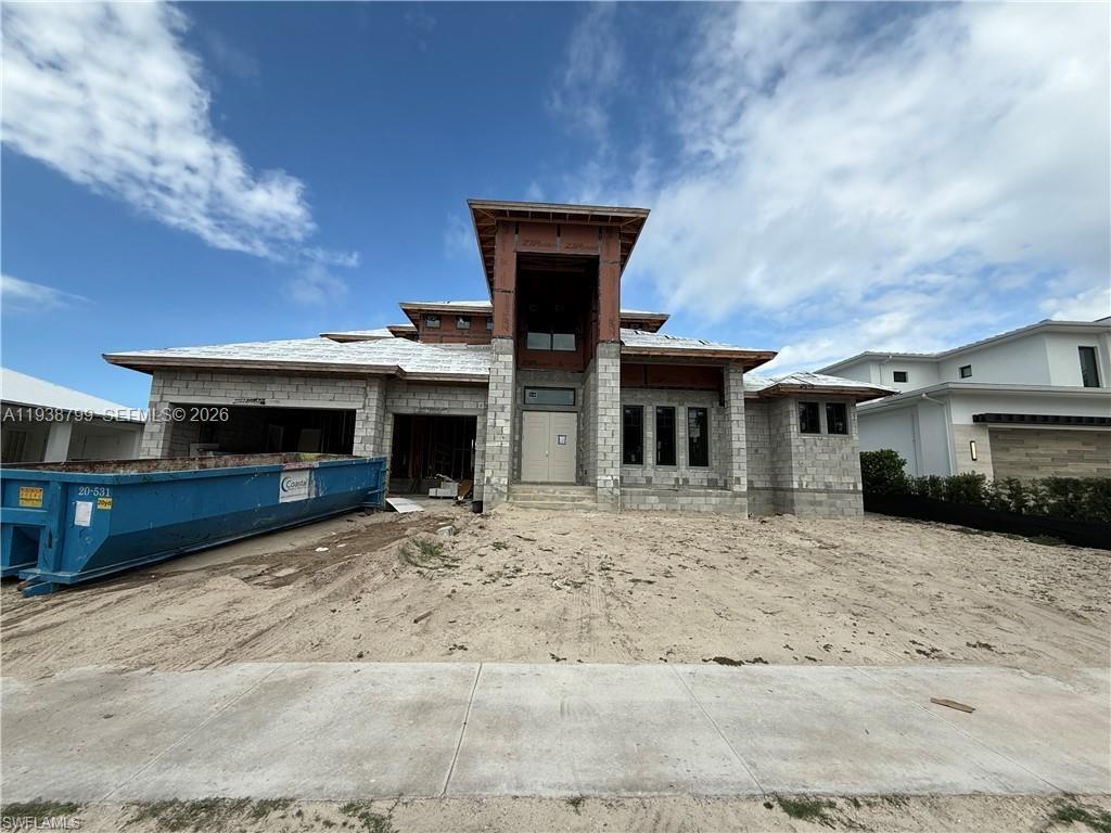 A partially constructed single-family home features concrete block walls and a blue dumpster out front — 654 Bamboo Ct, Marco Island FL 34145, MARCO ISLAND, FL