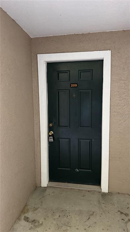 A dark green apartment door labeled 209 is set within a beige stucco exterior wall — 4209 WOODSTORKS WALK WAY UNIT 209, LUTZ, FL