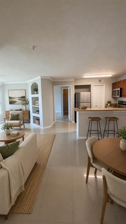 An open-concept living and dining area features tile floors, a kitchen island, and built-in shelving — 4209 WOODSTORKS WALK WAY UNIT 209, LUTZ, FL