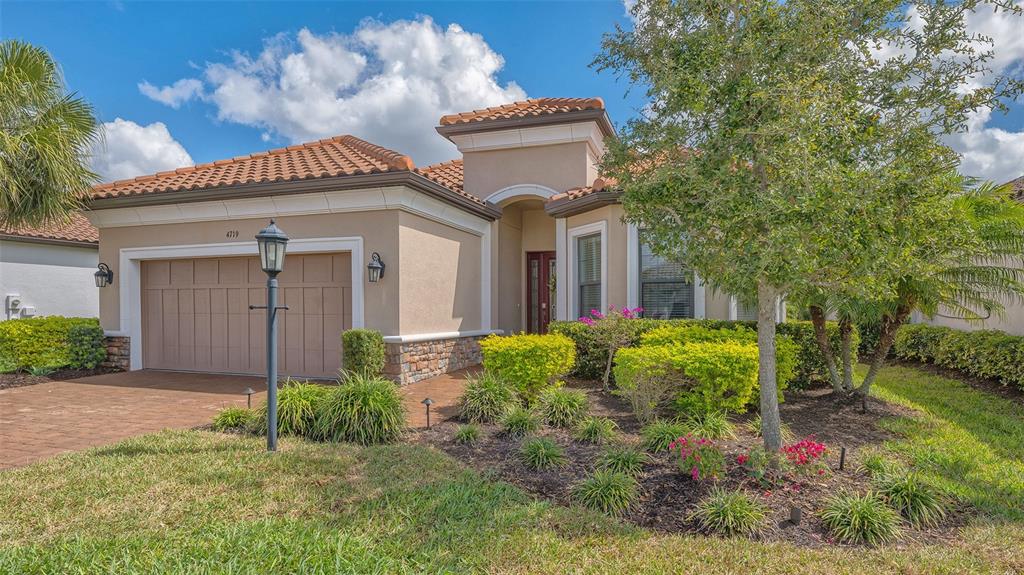 A single-story house with a tan stucco exterior, tile roof, and a two-car garage — 4719 CASSIO COURT, BRADENTON, FL
