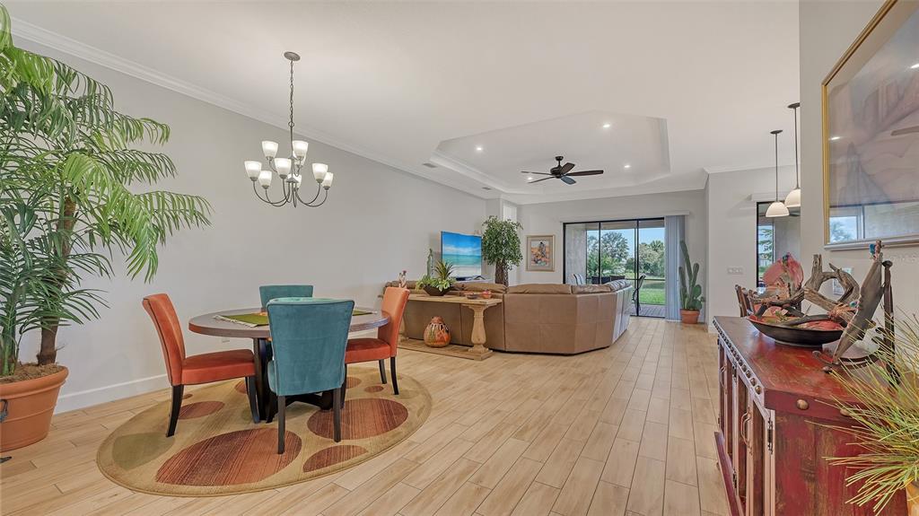 An open-concept living and dining area features tile flooring, a tray ceiling, and sliding glass doors — 4719 CASSIO COURT, BRADENTON, FL
