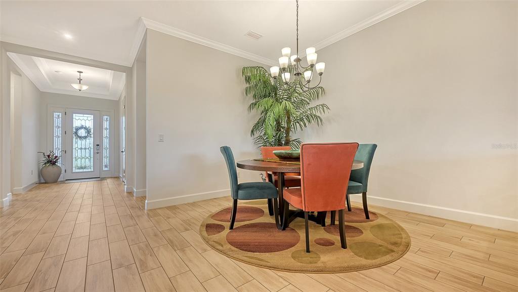 A dining area features a round table, colorful chairs, and a patterned rug on tile — 4719 CASSIO COURT, BRADENTON, FL