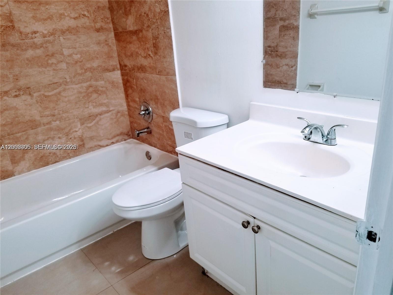 A bathroom features a white vanity, a toilet, and a bathtub with tan tiled walls — 6943 SW 40th St # R, Miramar FL 33023, MIRAMAR, FL