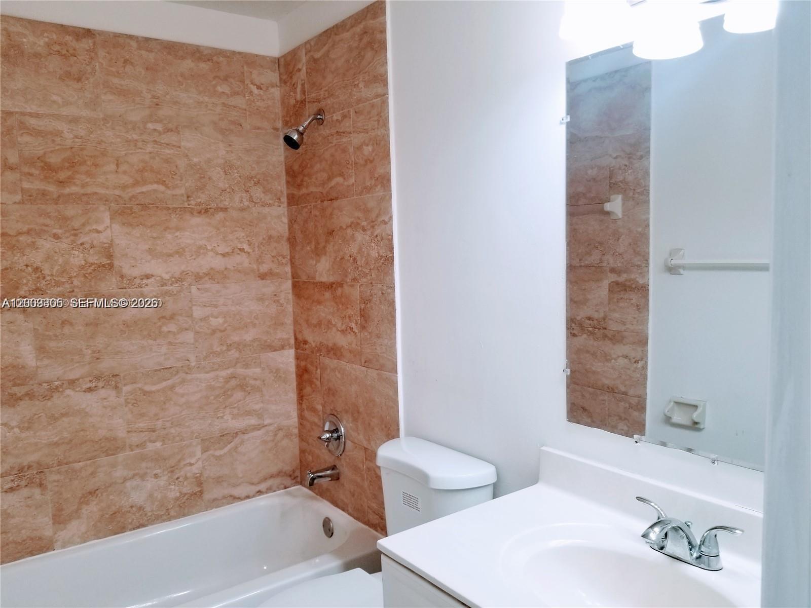 A bathroom features a white vanity, a toilet, and a bathtub with tan tiled walls — 6943 SW 40th St # R, Miramar FL 33023, MIRAMAR, FL